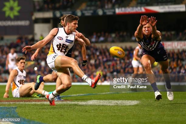 Ethan Hughes of the Dockers attempts to smother the kick by Luke Breust of the Hawks during the round 18 AFL match between the Fremantle Dockers and...