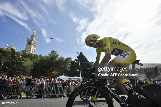 Great Britain's Christopher Froome, wearing the overall leader's yellow jersey, rides past the Notre-Dame de la Garde basilica as he competes in a...