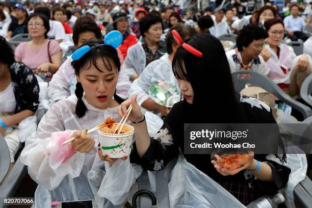 Korean women eats waiting the stage performance during the ceremony marking the 200 days to go to the PyeongChang Winter Olympic Games on July 22,...