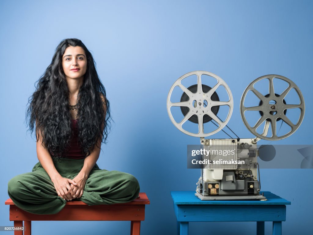 Portrait Of Young Woman With Long Black Hair Posing With Film Projector