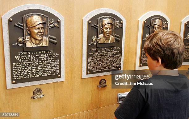 Young baseball fan looks at plaques of players inducted into the National Baseball Hall of Fame and Museum during the Baseball Hall of Fame weekend...