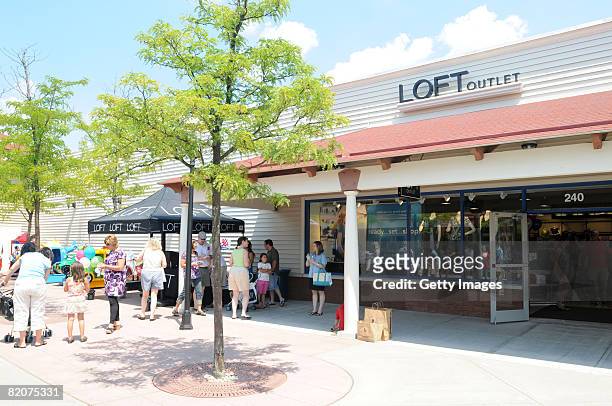 People stand in front of the store during an Ann Taylor LOFT grand opening at the Chelsea Wrentham Outlet July 26, 2008 in Wrentham, Massachusetts.
