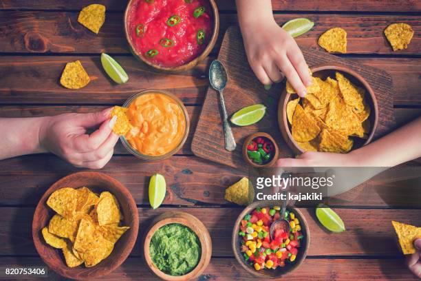 family eating nachos with sauces - mexican food party stock pictures, royalty-free photos & images