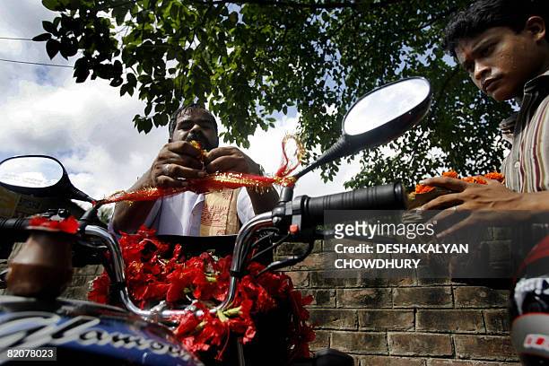 An Indian Hindu priest performs a ritual on a motorcycle believed to make it safe for its owner as he looks on at the Dakshineswar Kali Temple on the...