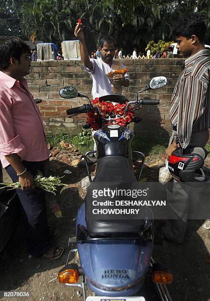 An Indian Hindu priest performs a ritual on a motorcycle believed to make it safe for its owner as he looks on at the Dakshineswar Kali Temple on the...