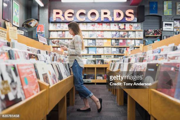 teenage girl in record store shopping for music - melody anderson stockfoto's en -beelden