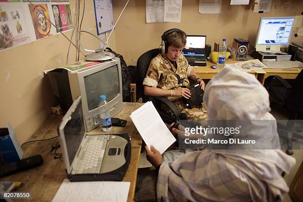 Royal Air Force Sgt. Alison Moore of the 15th Psychological Operations Group records a radio message with an Afghan interpreter at the British army...