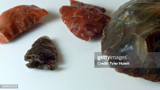 close up group native american artifacts hand axe ax red obsidian arrowhead jasper chert paiute indian stone tool in dirt from oregon great basin desert on white - chert stock pictures, royalty-free photos & images