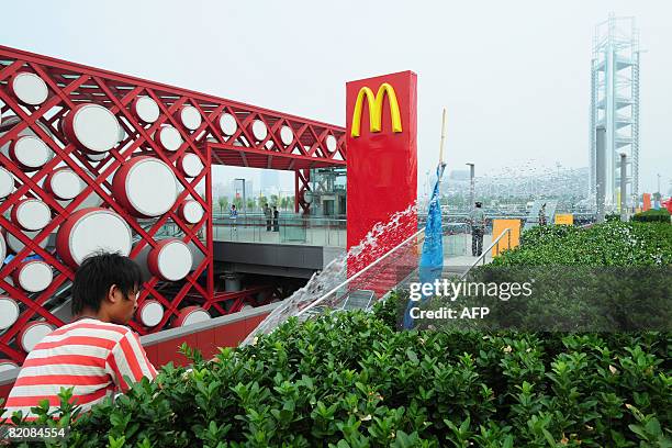 Plants are watered down beside an advertising sign for US fastfood giant McDonald's at a subway station on the Olympic Green in Beijing on July 28,...