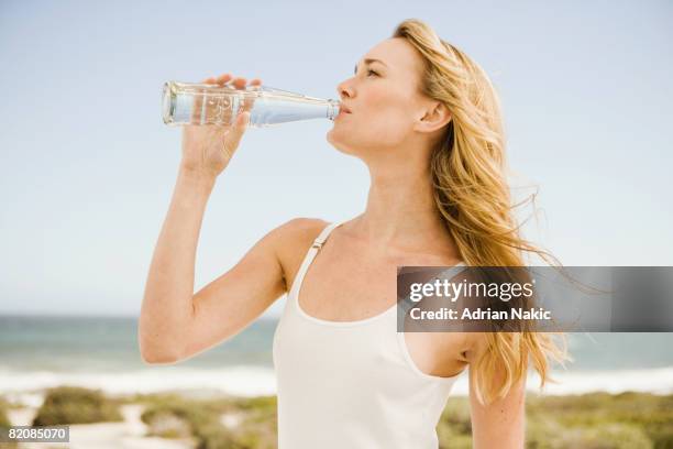 girl drinking from glass bottle at beach. - bottles glass top stockfoto's en -beelden