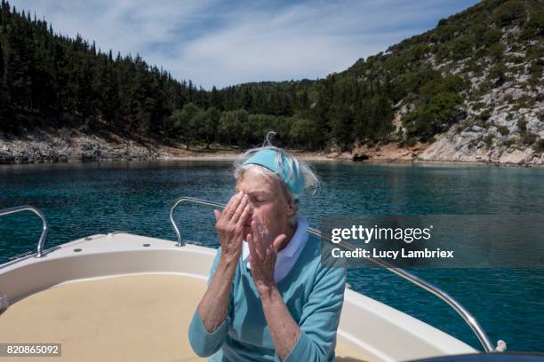 gritty women, senior woman putting on sunscreen lotion - fiskardo stockfoto's en -beelden