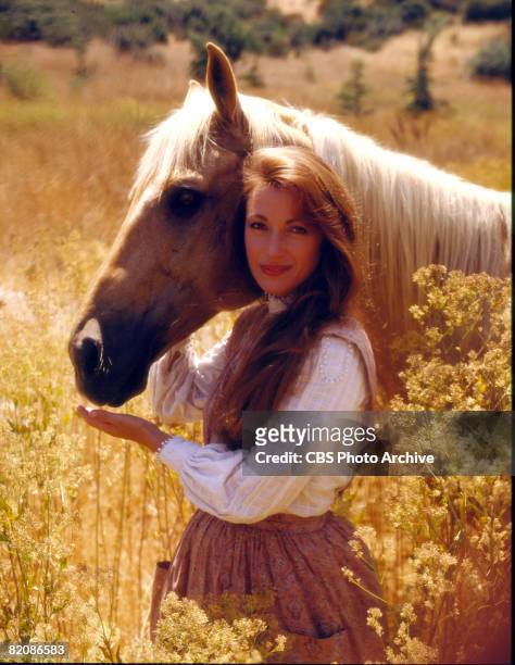 Promotional portrait of British actress Jane Seymour , as Dr. Michaela 'Mike' Quinn, as she poses with a horse in a field for the television series...