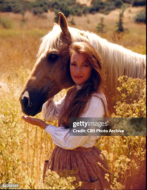 Promotional portrait of British actress Jane Seymour , as Dr. Michaela 'Mike' Quinn, as she poses with a horse in a field for the television series...