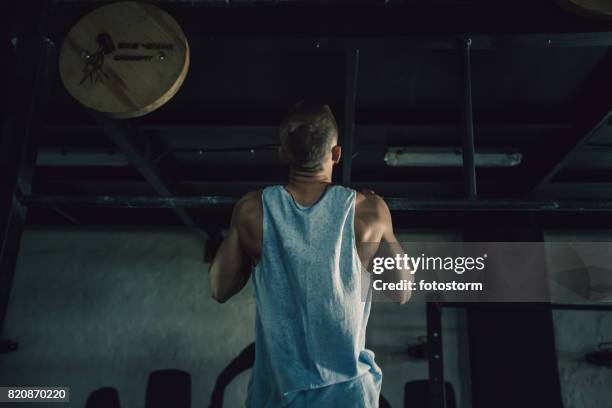 young man doing chin-ups in gym - chin ups stock pictures, royalty-free photos & images