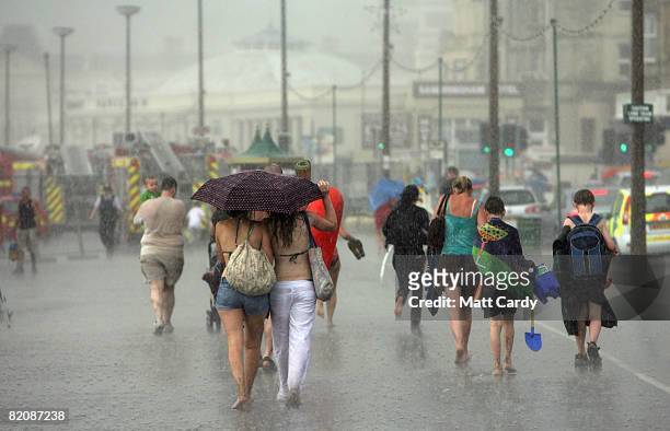 Holiday makers are caught in a sudden rain storm on the beach close to the Grand Pier on July 28 2008 in Weston-Super-Mare, England. A major fire has...