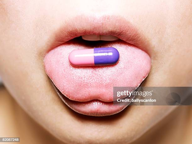 young asian woman with medical pill - human tongue foto e immagini stock