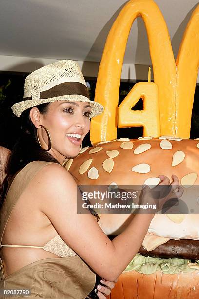 Kim Kardashian looks at a giant 'Big Mac' burger-themed birthday cake during the McDonald's Big Mac 40th Birthday Party at Project Beach House in...