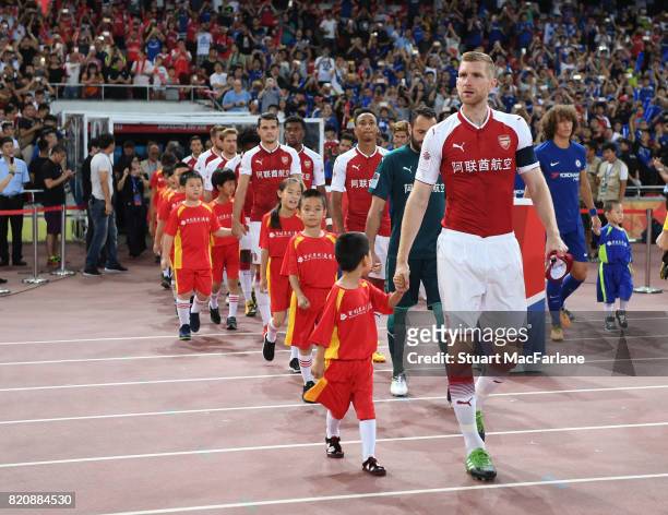 Arsenal captain Per Mertesacker leads out the team before the pre season friendly between Arsenal and Chelsea at the Birds Nest on July 22, 2017 in...