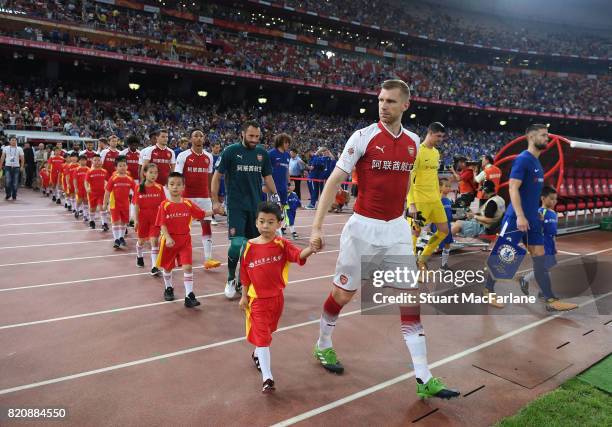 Arsenal captain Per Mertesacker leads out the team before the pre season friendly between Arsenal and Chelsea at the Birds Nest on July 22, 2017 in...