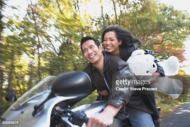 woman holding teddy bear on motorcycle with boyfriend - steve prezant stock pictures, royalty-free photos & images