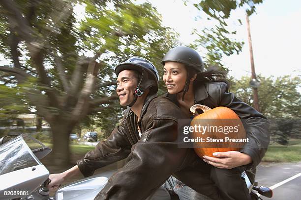 woman carrying pumpkin on motorcycle with boyfriend - steve prezant stock pictures, royalty-free photos & images