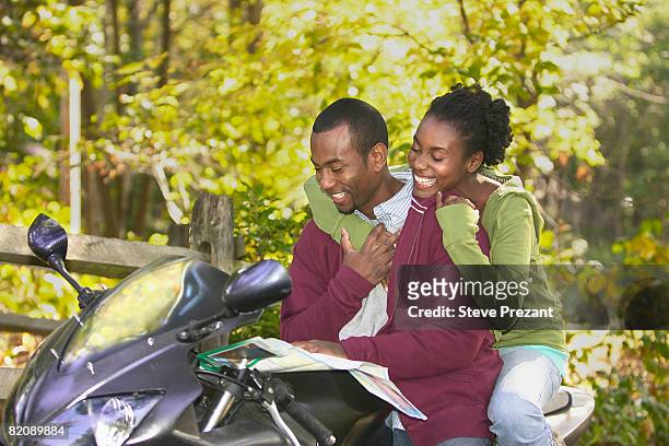 couple on motorcycle looking at map - steve prezant stock pictures, royalty-free photos & images