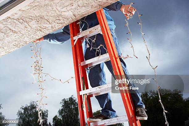 man hanging christmas lights - christmas decoration outdoor stock pictures, royalty-free photos & images