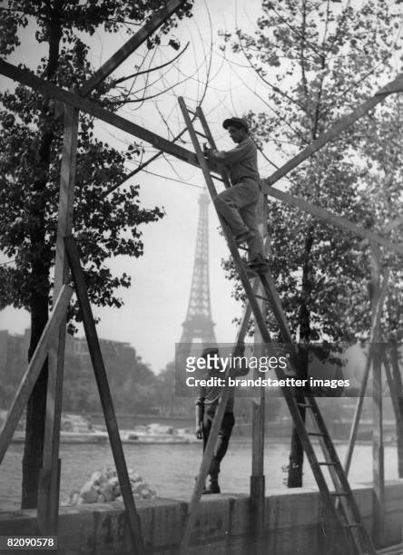 Workers during the construction of the pavilions for the gardening fair in Cours-La-Reine, in the background the Eiffel Tower, France, Photograph,...
