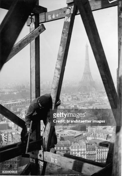 Construcion worker on the dome of Les Invalides in Paris, It has a height of 97 meter, In Background: the Eiffel Tower, Photograph, Around 1930 [Ein...