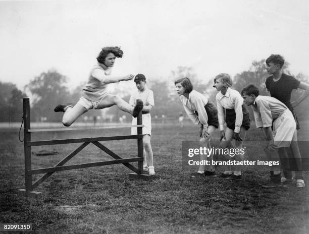 Norah Holden, school champion at hurdle run at her training, She is observed by her school mates, Photogaphy, May 24th 1930 [Norah Holden,...