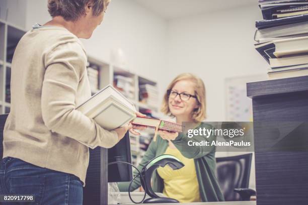 book lending,  librarian and an adult woman with books in library - exchanging books stock pictures, royalty-free photos & images