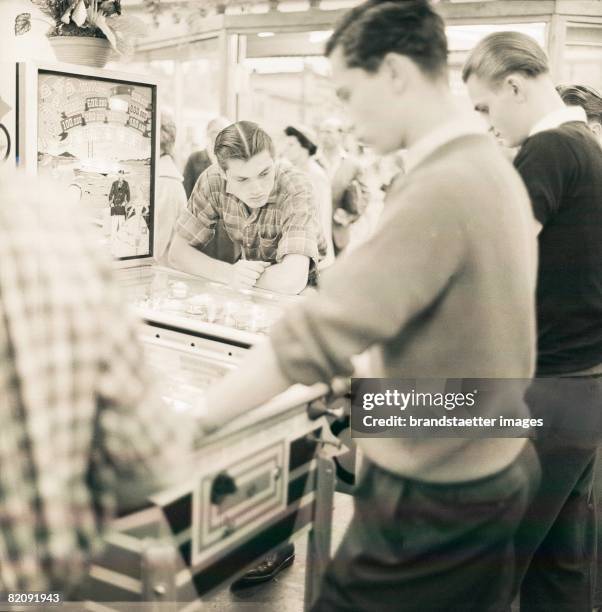 Young men at a pinball machine in an amusement arcade on Reeperbahn in Hamburg, Photograph, 1955/56 [Junge M?nner an einem Flipper in einer...