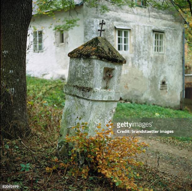 Weathered religious landmark in front of a house in Vestenpoppen at the river Thaya in the Austrian Waldviertel, Positioned at a small path, Autumnal...