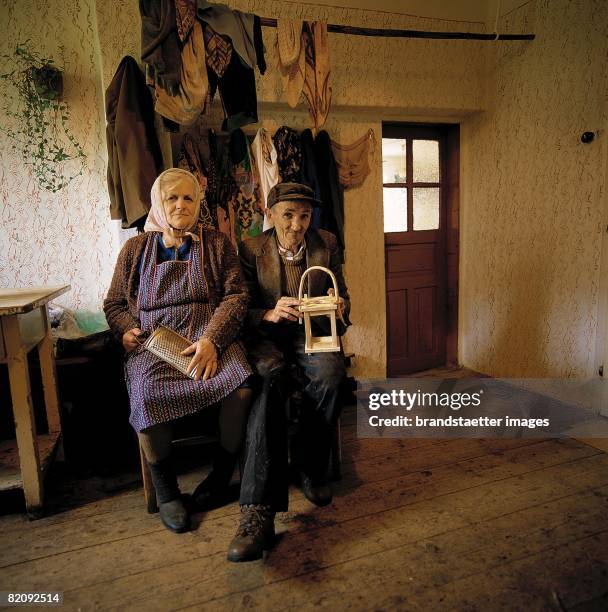 Peasants in the Austrian Waldviertel: The Neurreiter-couple sitting in their kitchen in front of the hung-up laundry and holding their working-tools,...