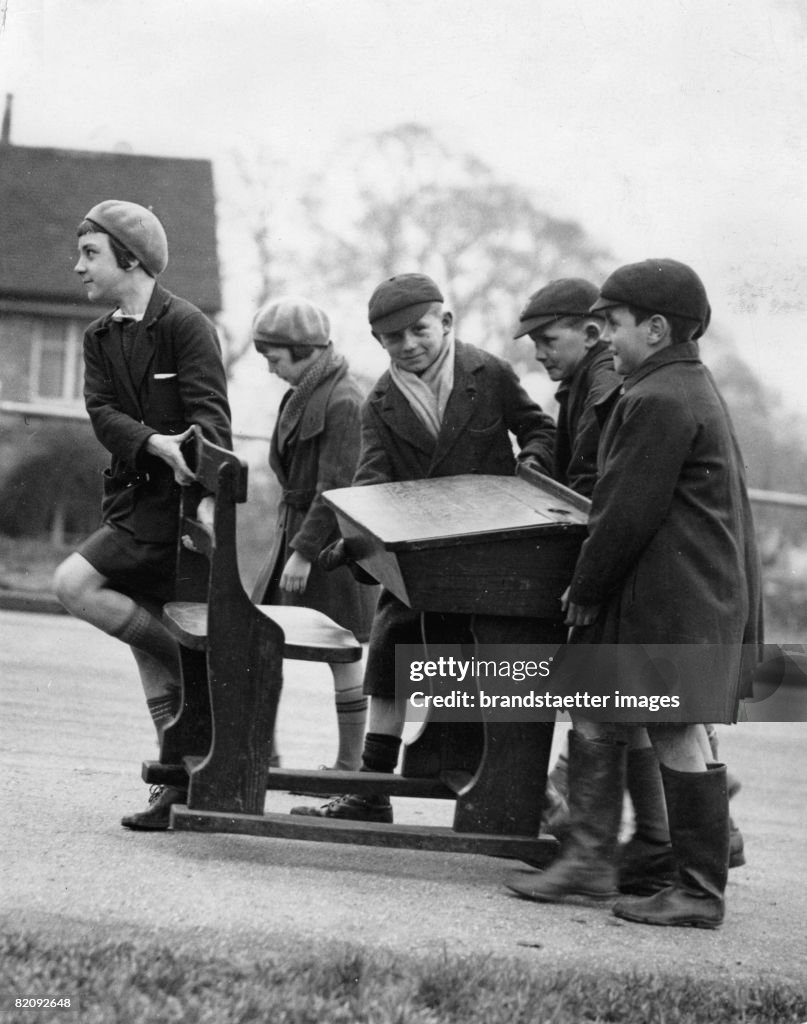 Children of the Loughton Council School have the opportunity to buy their old school desks, Five children carrying home a desk, Photograph, England, 5th March 1935