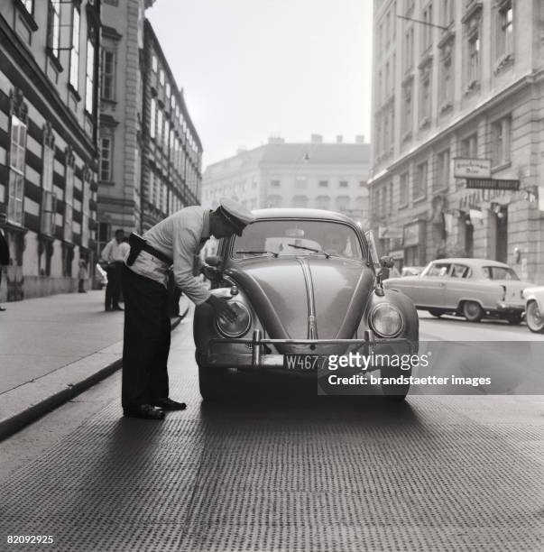 Campain for traffic safty in Vienna, Policeman cleaning headlights of a VW-Beatle, Photograph, Austria, Around 1959 [Aktion f?r Verkehrssicherheit in...