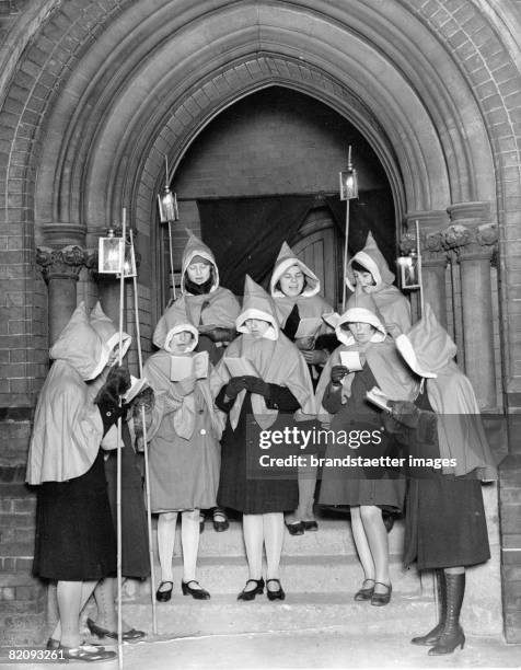 Women singing christmas carols on the steps of the church of Loughton, They are carrying laterns and singing in the roads to collect money for a good...