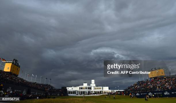Stormy clouds gather over the 18th hole and the Art-Deco-style clubhouse, as play comes to a close on day three of the Open Golf Championship at...