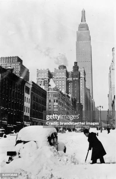 Snow in New York: after a surprising snowstorm a driver is clearing the way, In the background the Empire State Building, New York, USA, Photograph,...