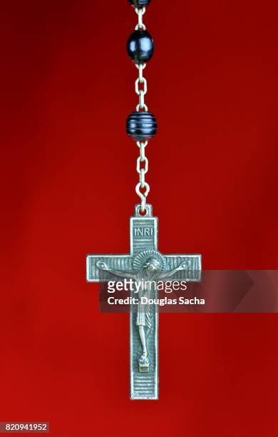 religious rosary praying beads on a red background - rosarios fotografías e imágenes de stock
