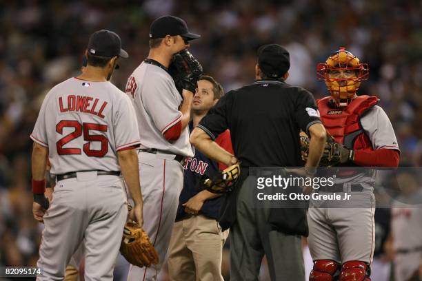 Jon Lester of the Boston Red Sox confers with the trainer and teammates on the mound during their MLB game against the Seattle Mariners on July 21,...
