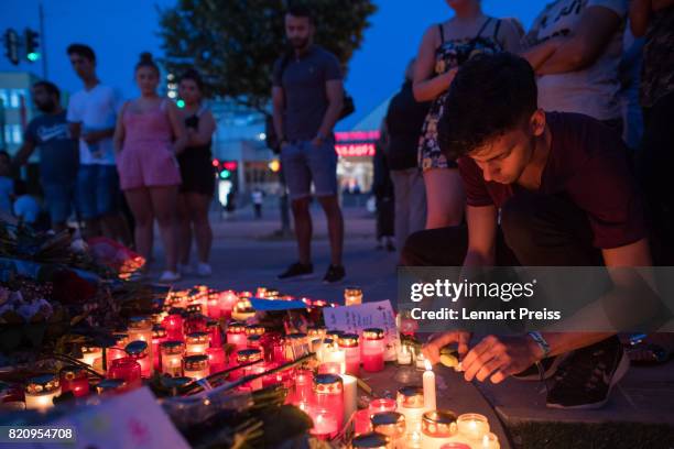 Mourner lights a candle at a memorial to commemorate the victims of the shooting spree that one year ago left ten people dead, including the shooter,...