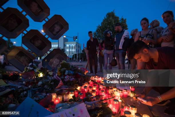 Mourner lights a candle at a memorial to commemorate the victims of the shooting spree that one year ago left ten people dead, including the shooter,...