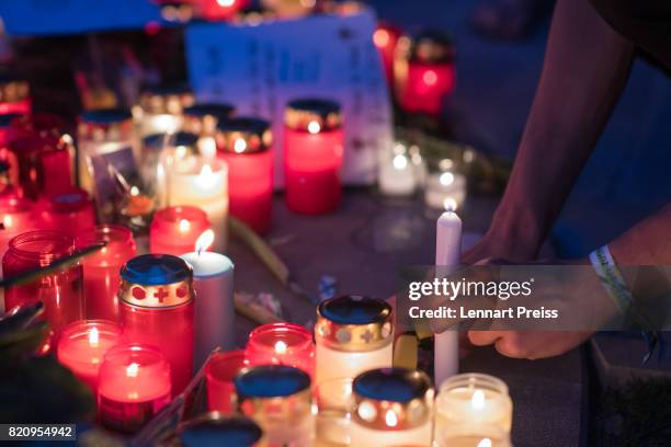 Mourner lights a candle at a memorial to commemorate the victims of the shooting spree that one year ago left ten people dead, including the shooter,...