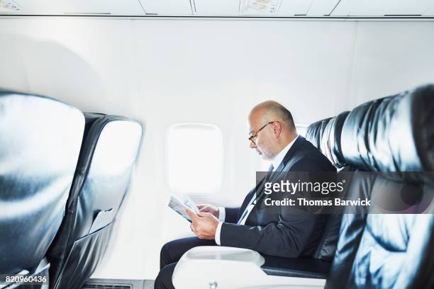Businessman reading a magazine while traveling on airplane on business trip