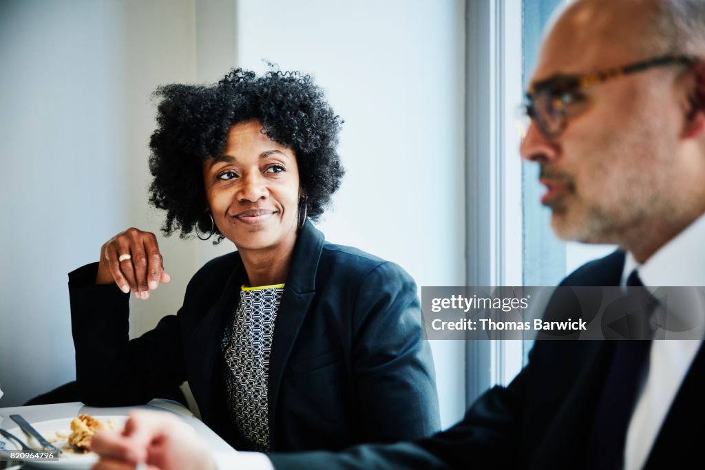 Smiling businesswoman in discussion with colleague during lunch