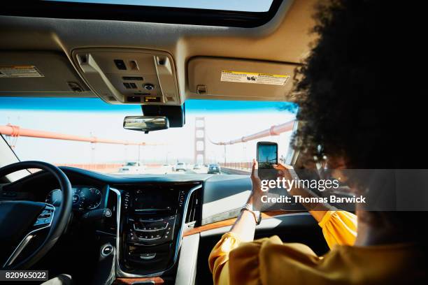 woman taking photo with smartphone while riding in car across golden gate bridge - passenger point of view bildbanksfoton och bilder