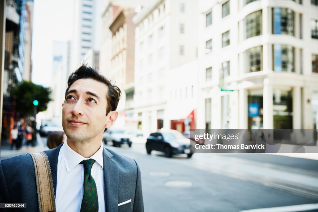 Businessman on downtown street looking at city skyline