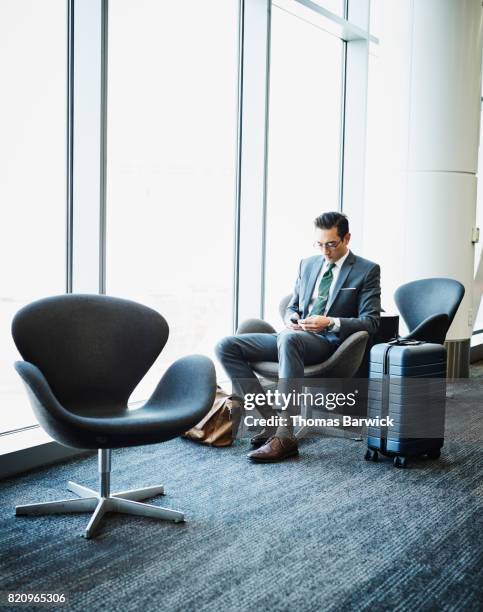 businessman working on smartphone while waiting for flight in airport - gate imagens e fotografias de stock