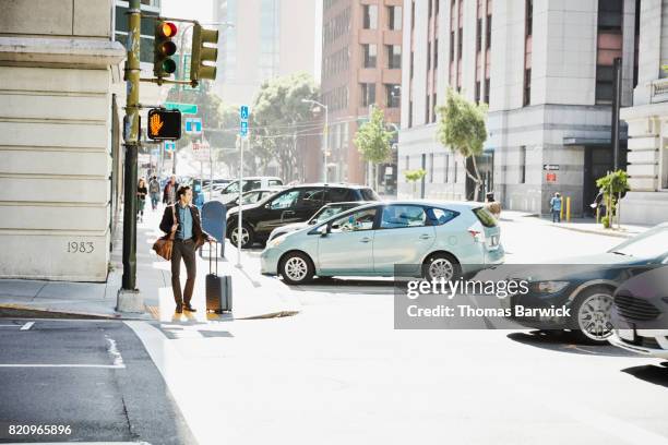 businessman with luggage waiting to cross city street - car parked stock pictures, royalty-free photos & images